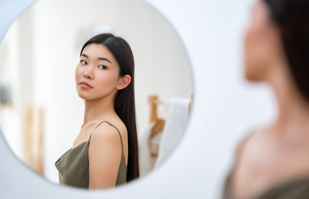 Japanese woman looking at her reflection, self-care concept. 